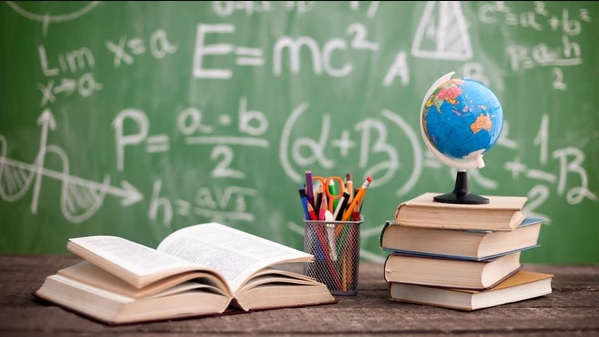 La educación en su reflejo sobre una pizarra llena de fórmulas acompañada con un globo terráqueo y libros